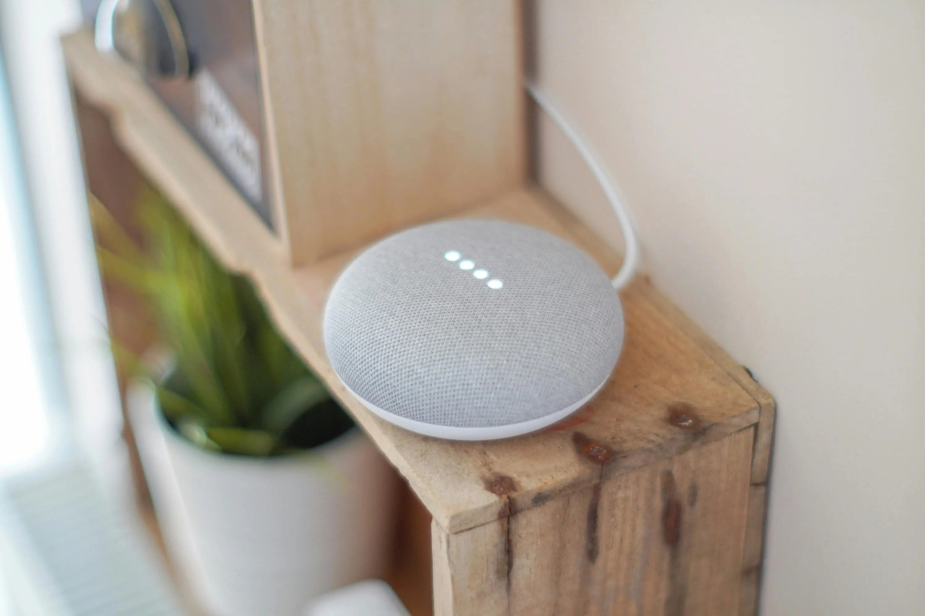 Smart Gadgets smart speaker with fabric cover and glowing LED dots on a wooden shelf.