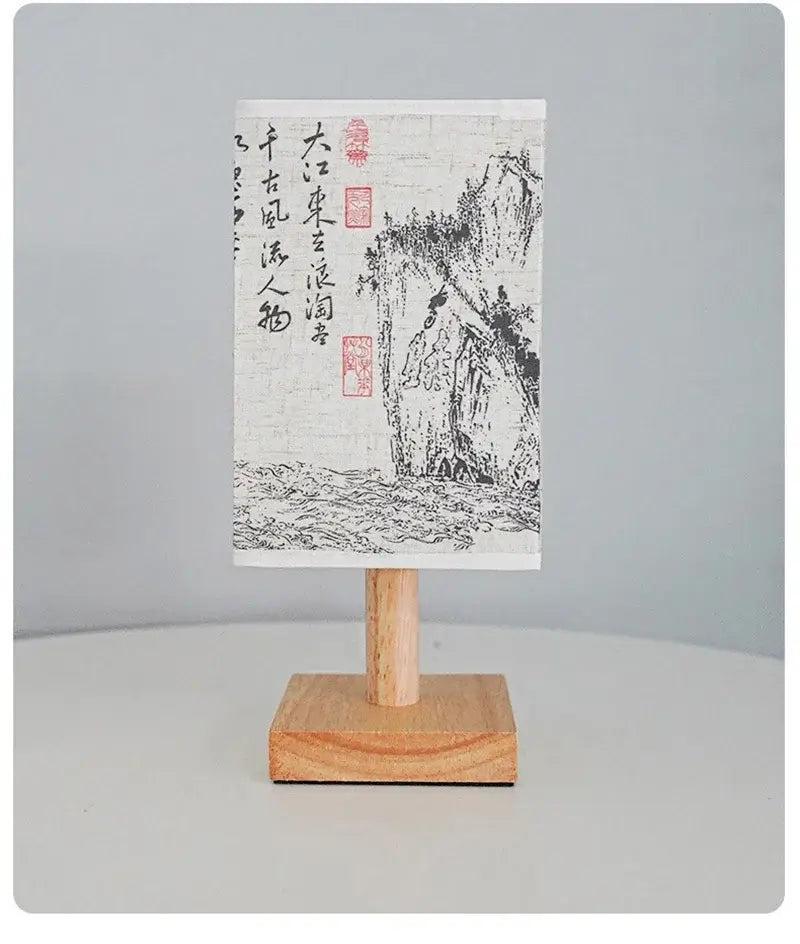 Chinese style artwork on a small wooden stand featuring landscape design with characters.