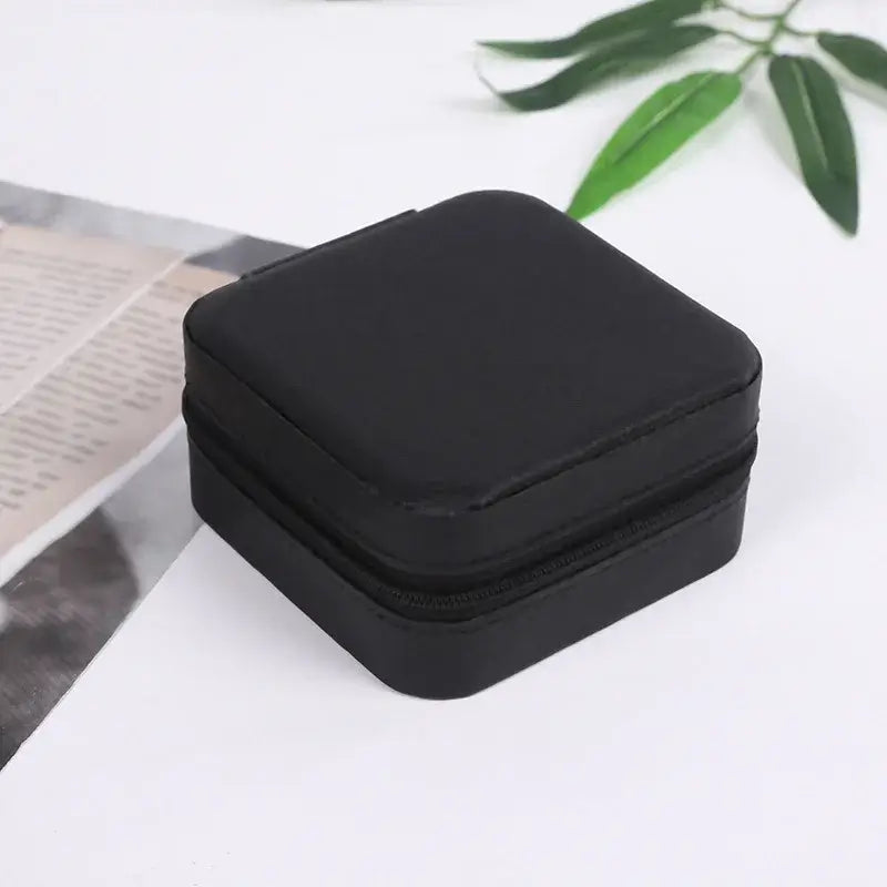 Compact travel jewelry organizer in sleek black leather, perfect for storing rings and small jewelry on the go.