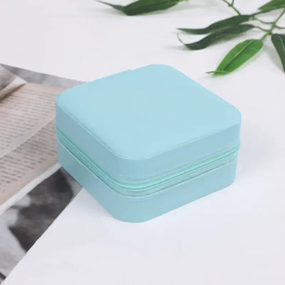 compact travel jewelry organizer in light blue color on a white surface with greenery and a magazine.