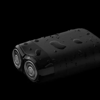 Xiaomi Mijia S100 electric shaver with waterproof design, showcasing twin blades and droplets on a sleek black surface.