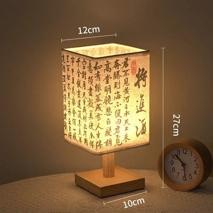 LED table lamp ambient glow with Chinese style fabric shade and wooden base on bedside table.