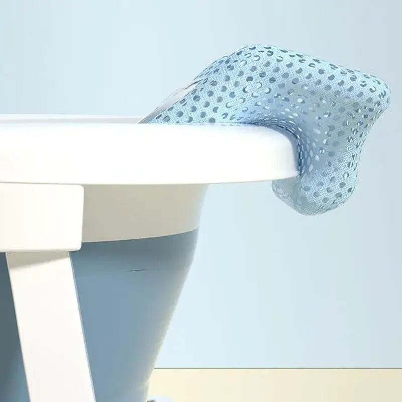 Newborn baby bath net draped over a bath tub edge, showcasing its soft cloth padding and ergonomic design for safe bathing.
