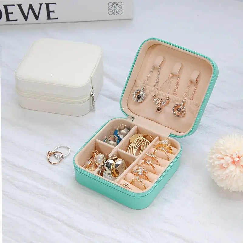 Compact travel jewelry organizer featuring a stylish turquoise leather case showcasing rings and earrings in an organized layout.