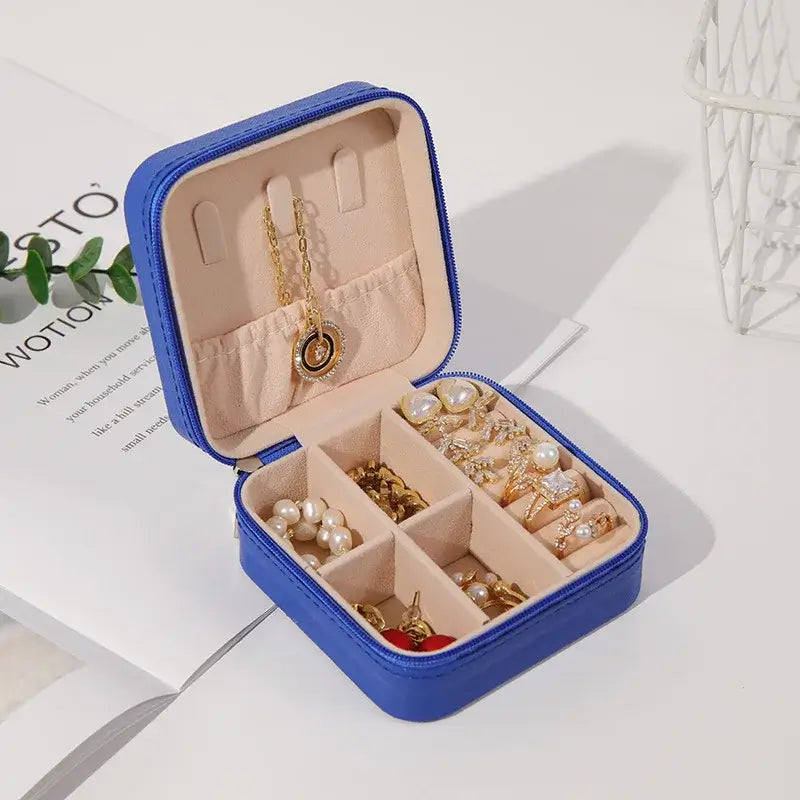compact travel jewelry organizer containing earrings, necklaces, and rings in a stylish blue leather case