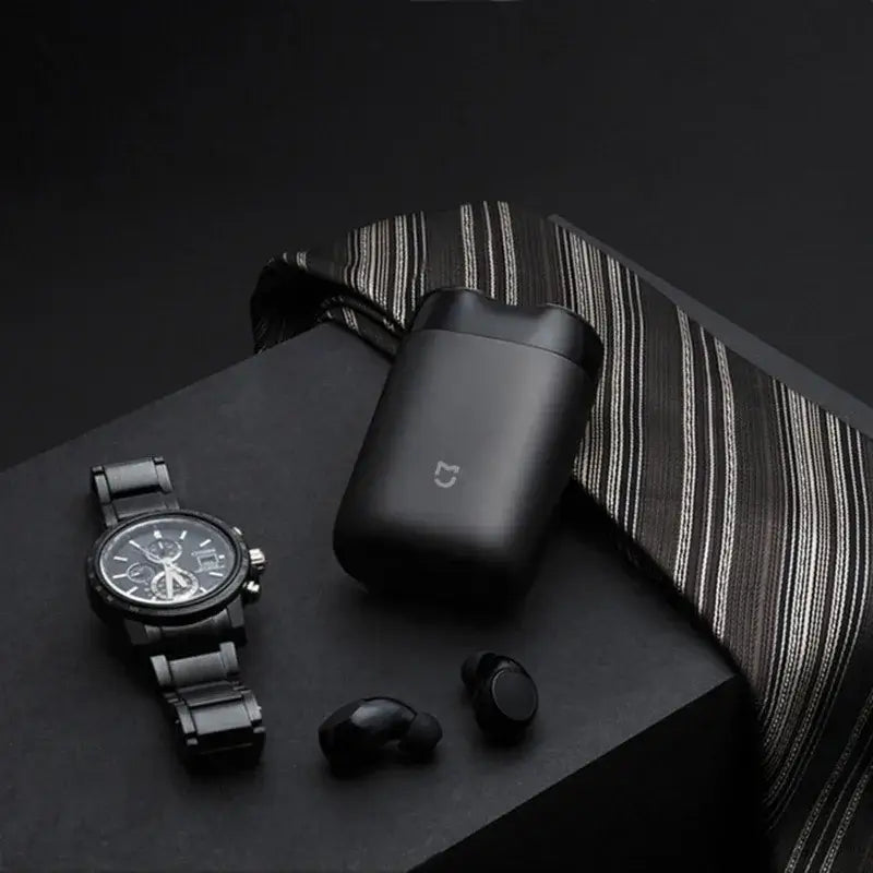 XIAOMI MIJIA S100 electric shaver case with black watch and wireless earbuds on dark background