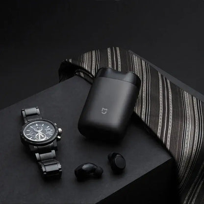 XIAOMI MIJIA S100 electric shaver case with black watch and wireless earbuds on dark background