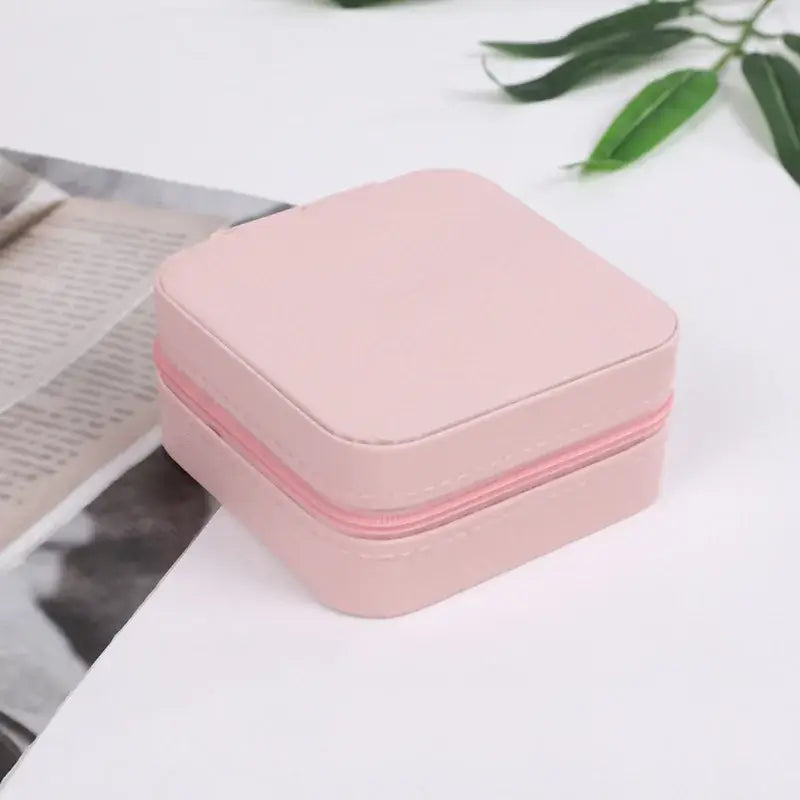 Compact travel jewelry organizer in blush pink leather with zipper, perfect for storing rings and small jewelry while traveling.